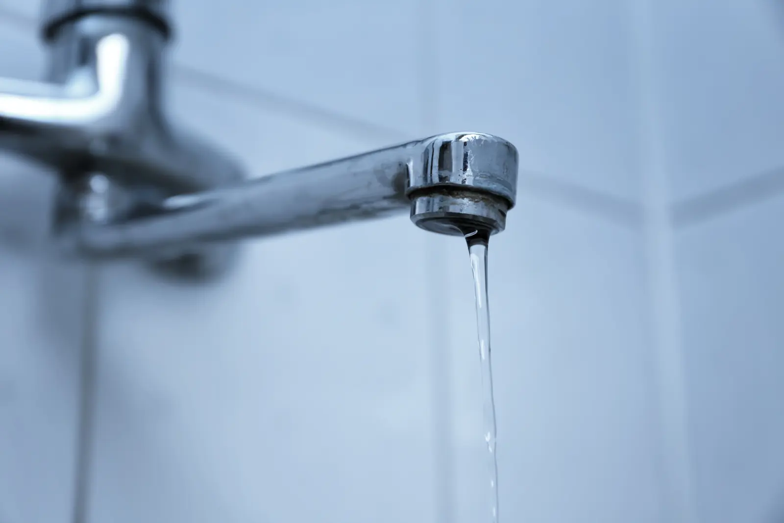 Robinet de salle de bains d'où coule un filet d'eau